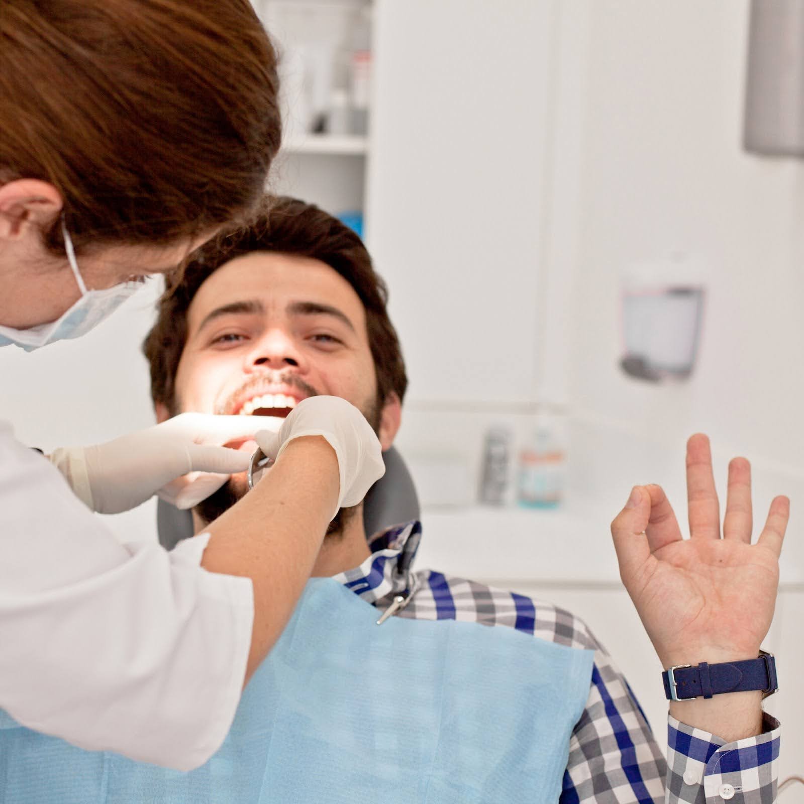 Patient giving an OK sign while their braces are checked