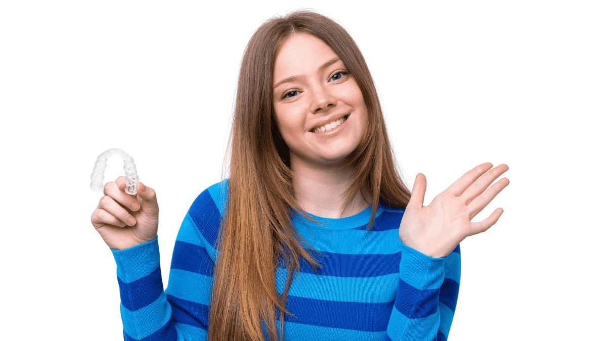Patient smiling while holding a clear Invisalign aligner